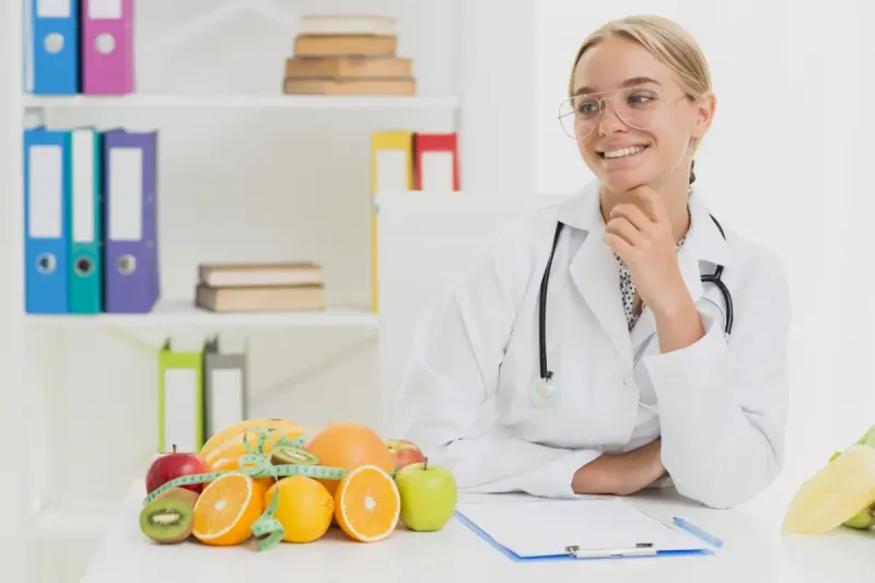 Nutrióloga escribiendo en una libreta junto a una mesa con alimentos saludables.